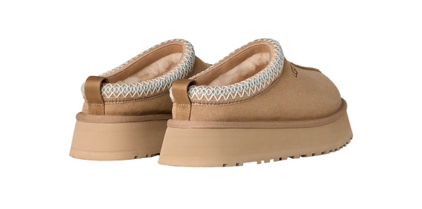 Pair of tan slippers with white fur lining on a light gray background