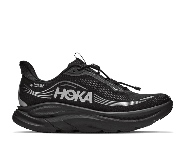 A black running shoe with a thick black sole and silver wavy stripe accents on the side,