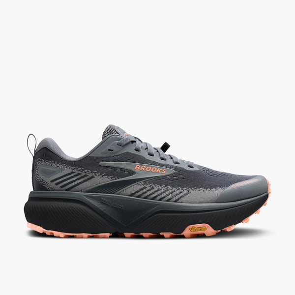 Brooks trail running shoe in dark gray and black with a coral pink outsole, shown from a three-quarters angle on a light gray background.
