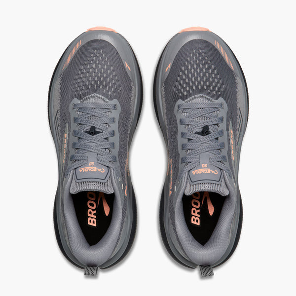 A pair of Brooks Cascadia trail shoes shown from a top-down view, featuring a dark gray mesh upper with peach accents on the outsole and tongue branding.