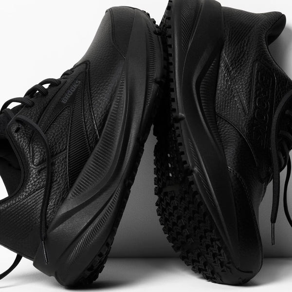 A pair of black athletic shoes with textured leather and rubber soles, shown from side and bottom angles against a light gray background.