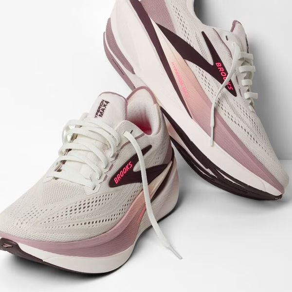 Pair of white and pink running shoes with 'Brooks' branding on a light background