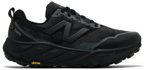 A black New Balance trail running shoe with a dark gray 'N' logo, black laces, and a black Vibram outsole, shown from a side profile on a white background.