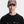 Person wearing a black t-shirt with a logo and a grape colored cap on a white background