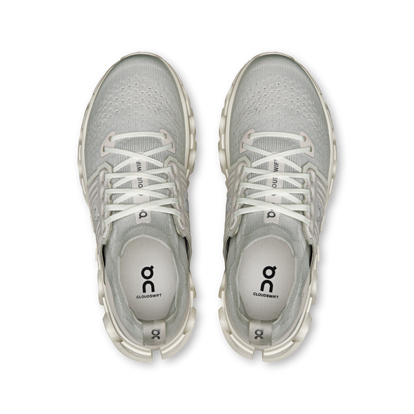 Pair of gray athletic shoes with white laces on a white background