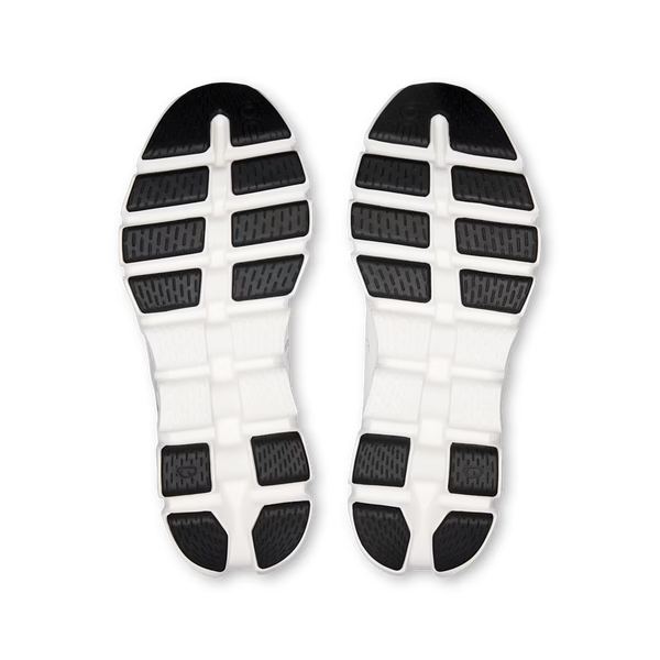 A pair of white athletic shoe soles shown from above, featuring black textured grip pads arranged in a grid pattern.