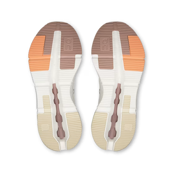Top-down view of a pair of athletic shoes showing the textured outsoles. The soles feature a color-blocked design with white, beige, brown, and orange sections.