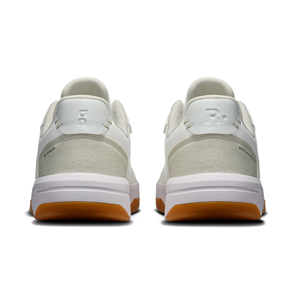 A pair of Puma sneakers shown from the back, featuring off-white leather and suede uppers with a white midsole and a gum brown outsole.