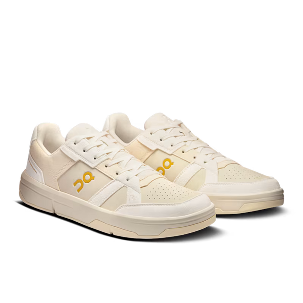 Pair of cream-colored sneakers with a brand logo on a white background