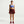 Woman wearing a blue sports bra and maroon skirt on a white background