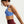Woman wearing a blue sports bra and maroon leggings on a light gray background