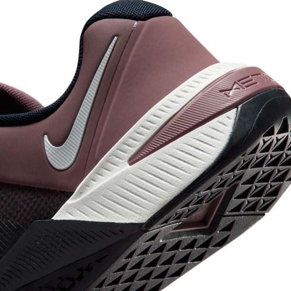 Close-up of a maroon athletic shoe with a white sole and black tread pattern.