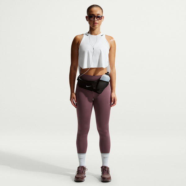 Person wearing a white sleeveless top and maroon leggings with a waist bag on a light gray background