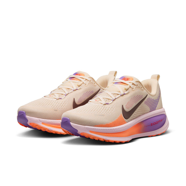 A pair of Nike running shoes with a beige upper and multicolored pop colors.