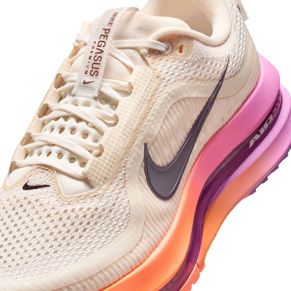 Beige running shoe with pink and orange sole on a white background