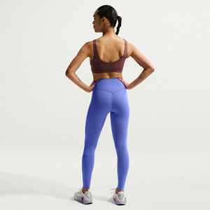 Woman wearing a brown sports bra and blue leggings on a white background
