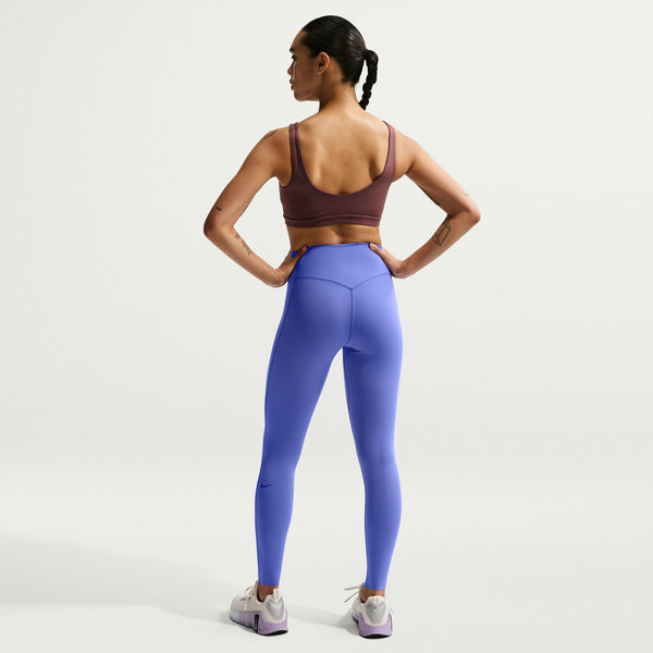 Woman wearing a brown sports bra and blue leggings on a white background