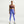 Woman wearing a brown sports bra and purple leggings on a white background
