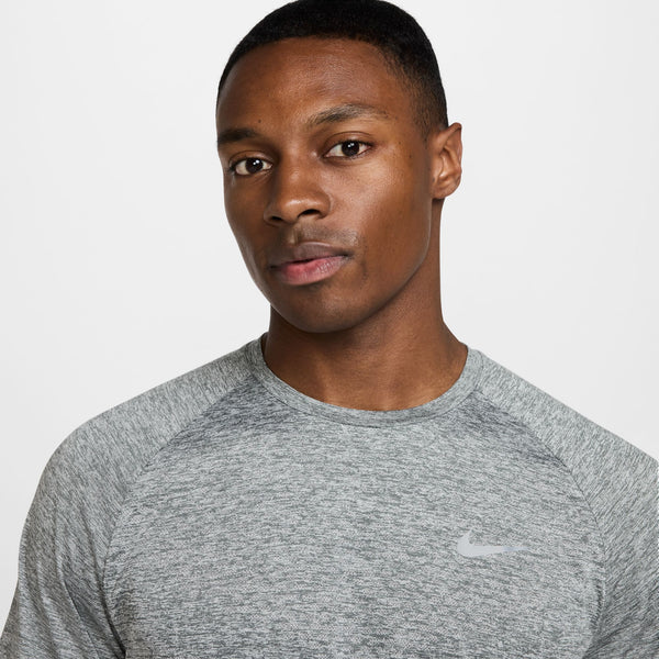Man wearing a gray Nike athletic shirt on a white background