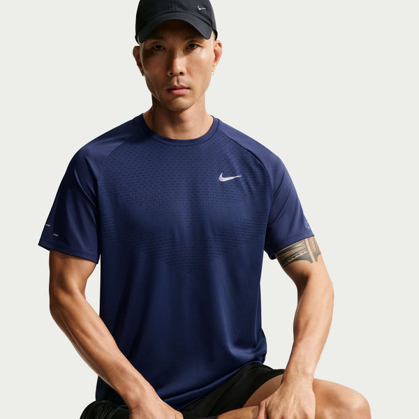 Man wearing a navy blue Nike t-shirt and black cap on a light gray background