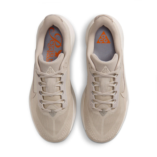Top down look at a beige sneakers with orange accents on a white background