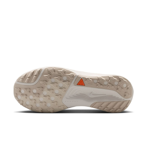 Close-up of a beige athletic shoe sole with a red triangle logo on a white background