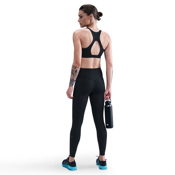 Woman wearing black athletic outfit holding a water bottle on a white background