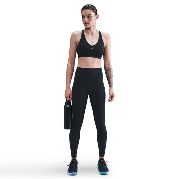 Woman wearing a black sports bra and leggings holding a water bottle on a white background