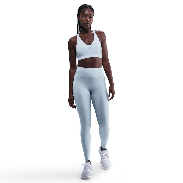 Woman wearing a light blue Nike sports bra and leggings on a white background