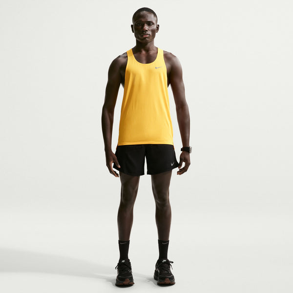 Man wearing a yellow tank top and black shorts on a white background
