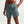 Person wearing teal athletic shorts with a Nike logo on a light gray background