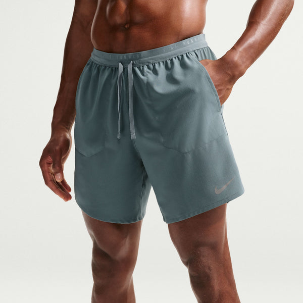 Person wearing teal athletic shorts with a Nike logo on a light gray background