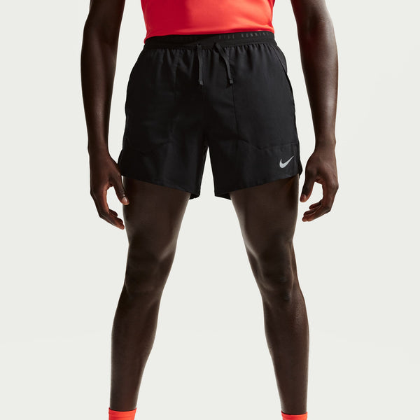 Person wearing black athletic shorts with a Nike logo on a light gray background