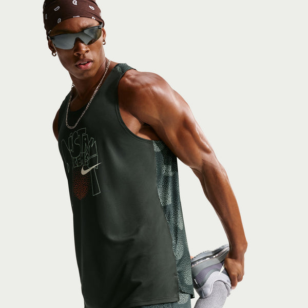 Man wearing a green Nike tank top and gray shorts on a white background