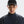 Person wearing a dark jacket and cap with a brand logo on a light gray background