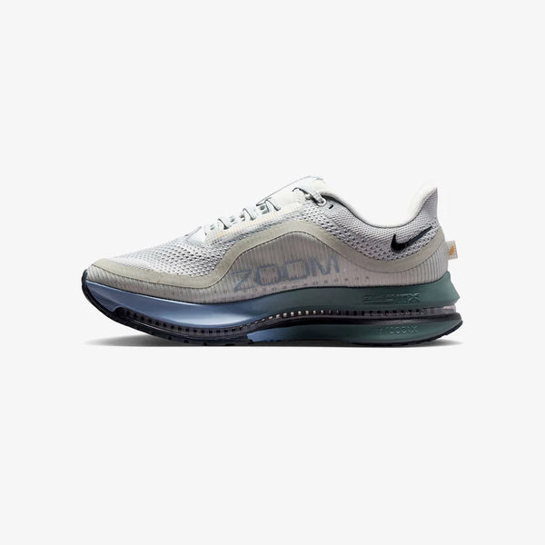 Grey, green, and blue running shoe on a white background