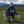 This picture is hilarious.  It shows a young man wearing 990's sitting in a green grass field with a goat