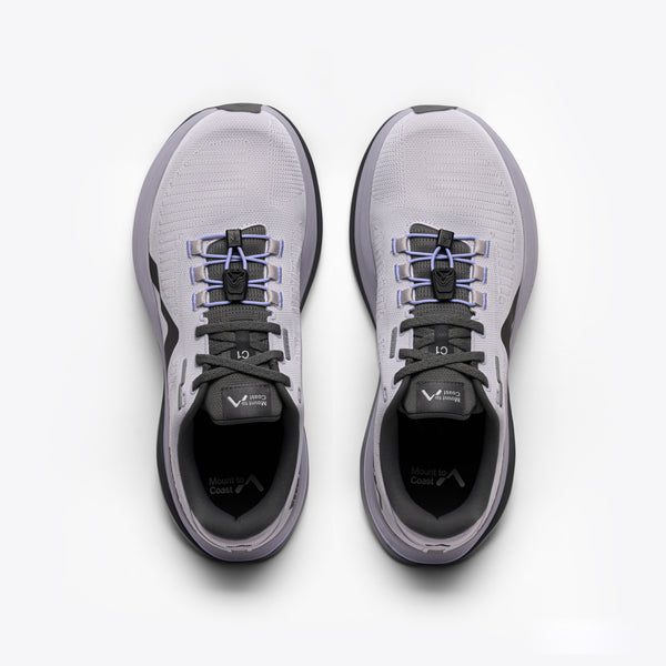 A light gray and purple running shoe with a dark gray sole and logo, featuring the text 'Mount to Coast' on the side