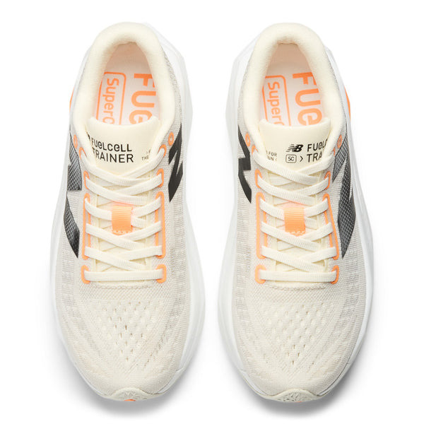 A pair of New Balance women's running trainers with white uppers, black, orange, and yellow accents, and a gray outsole.