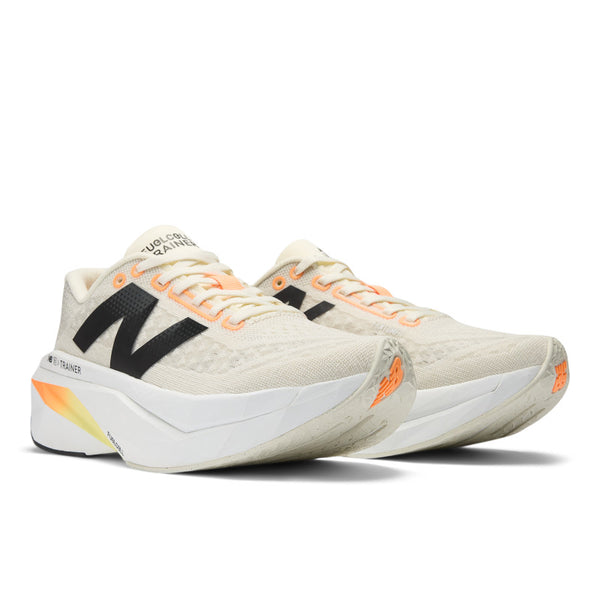 A pair of New Balance women's running trainers with white uppers, black, orange, and yellow accents, and a gray outsole.
