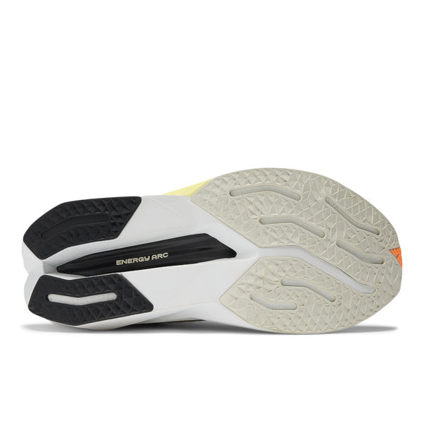 A pair of New Balance women's running trainers with white uppers, black, orange, and yellow accents, and a gray outsole.