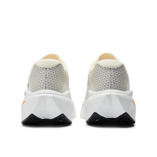 A pair of New Balance women's running trainers with white uppers, black, orange, and yellow accents, and a gray outsole.