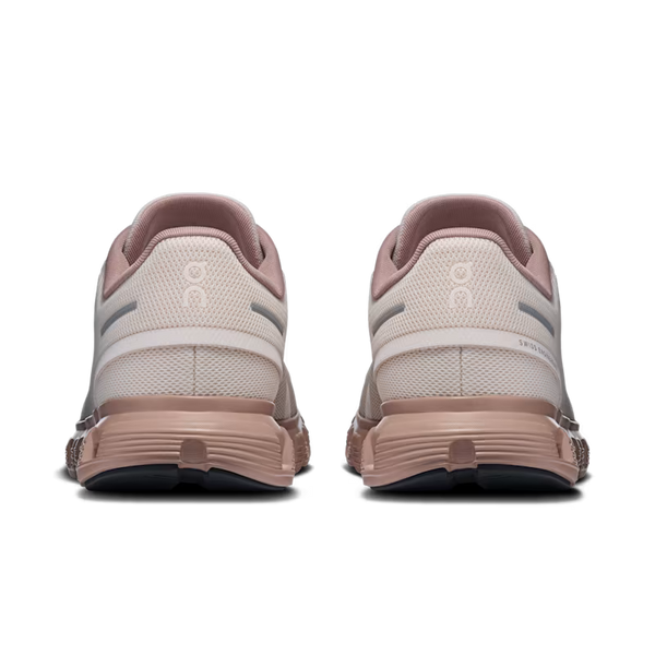A pair of On running shoes shown from the back, featuring a light pink and beige mesh upper with a dusty rose sole and heel accents.