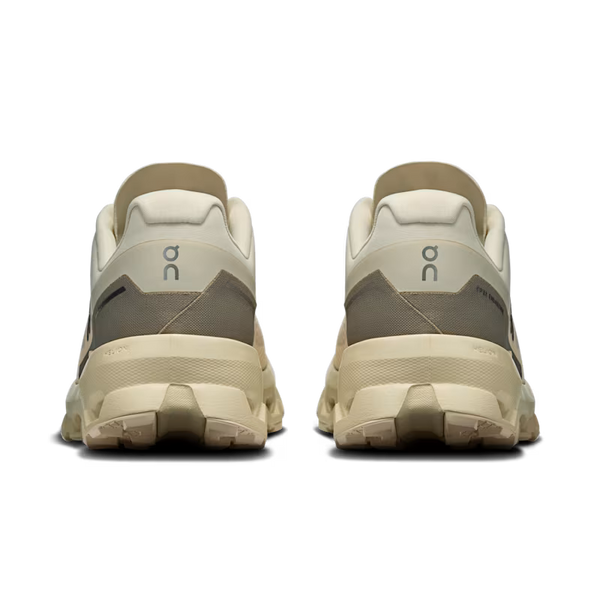 Pair of beige and gray athletic shoes on a white background with On brandlogo's near each heel.
