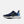 A New Balance athletic sneaker in navy blue with a light blue mesh heel, a prominent yellow outlined 'N' logo, and a thick white midsole, shown from a side profile on a light gray background.