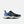 A New Balance running shoe in navy blue, light blue, and white with neon yellow accents, shown from a side profile on a light gray background.