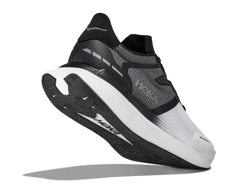 Back angled view of the Unisex Transport X by HOKA in the color Black / White