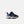 A toddler's New Balance sneaker in navy blue and light blue mesh, featuring a bright yellow 'N' logo and a yellow pull tab, set against a light gray background.