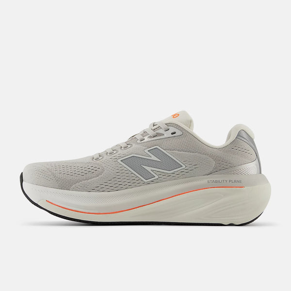 The medial side of this men's new balance shoe has a orange stripe between teh midsole layers.