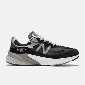Dark gray and black 990v6 athletic shoe with orange accents on a white background